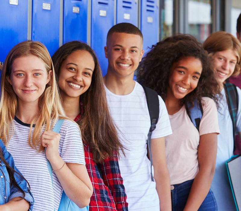 A multi-ethnic group of high school students stand in front of a row of lockers in a Bend, Oregon high school