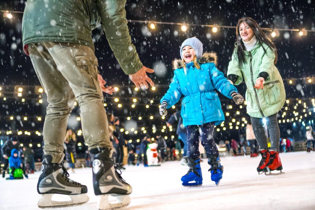 A girl ice skates with her parents on an ice rink in downtown Bend, Oregon. 