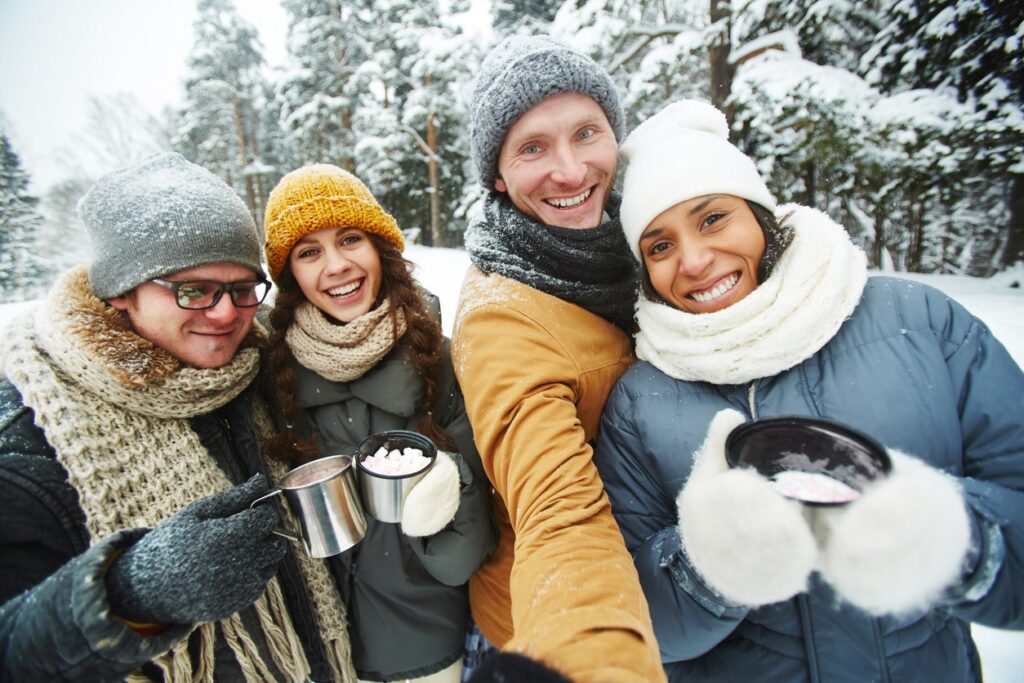 A group of friends on a snowy winter hike in Bend, Oregon enjoy a cup of hot cocoa. 