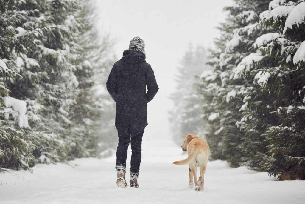 A woman and her dog take a snowy winter hike in Bend, Oregon.